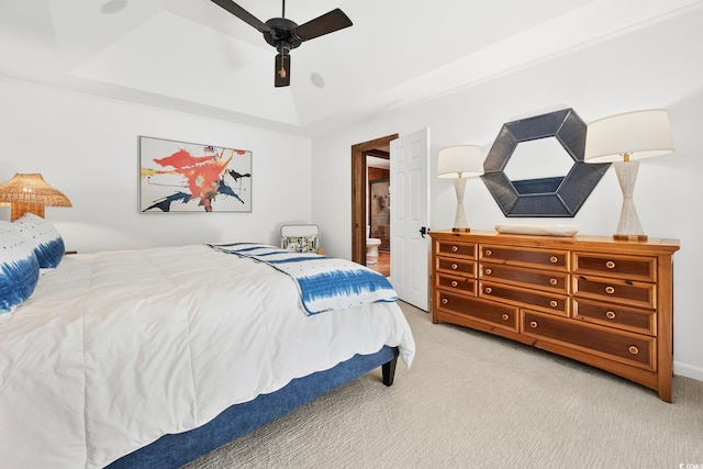 bedroom with a tray ceiling, ensuite bathroom, a ceiling fan, and carpet