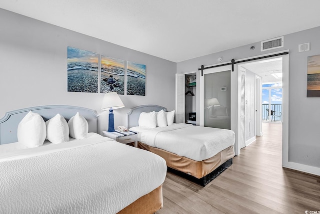 161 Sea Watch Dr Unit 614, Myrtle Beach, SC 29572 - bedroom with a barn door, light wood finished floors, and baseboards