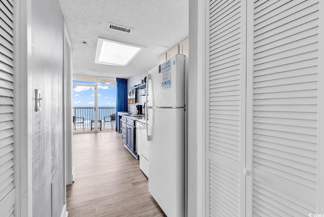 161 Sea Watch Dr Unit 614, Myrtle Beach, SC 29572 - kitchen featuring freestanding refrigerator, expansive windows, a textured ceiling, light wood-type flooring, and dishwashing machine