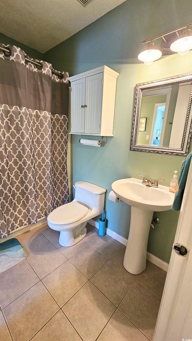 5 Gate 1 Unit 5, Calabash, NC 28467 - bathroom featuring tile patterned floors, curtained shower, baseboards, toilet, and a textured ceiling