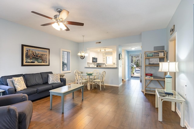 living room with plenty of natural light, ceiling fan, baseboards, and dark wood-type flooring