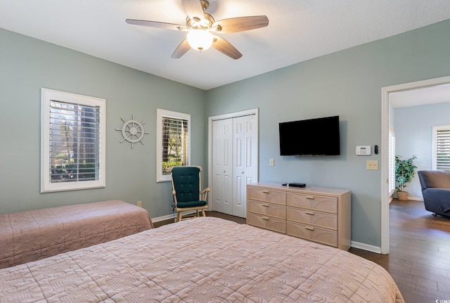bedroom with dark wood-style floors, baseboards, a closet, and a ceiling fan