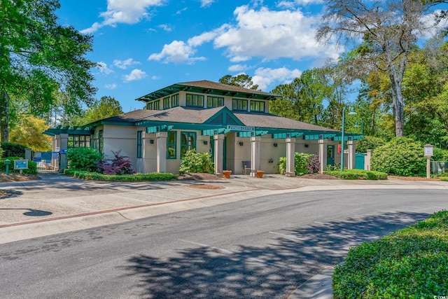prairie-style home featuring a gate, stucco siding, and fence