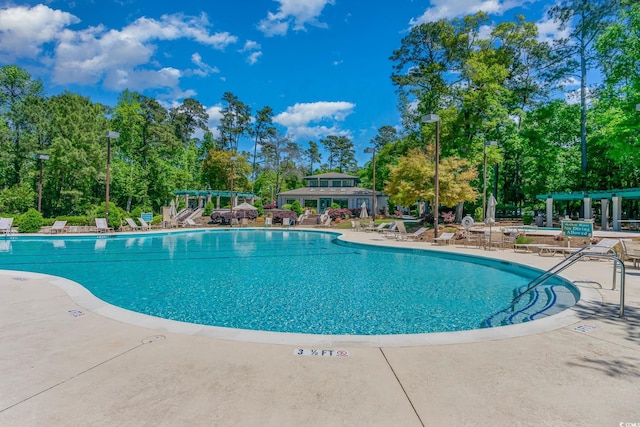 community pool with a pergola, a patio, and view of scattered trees