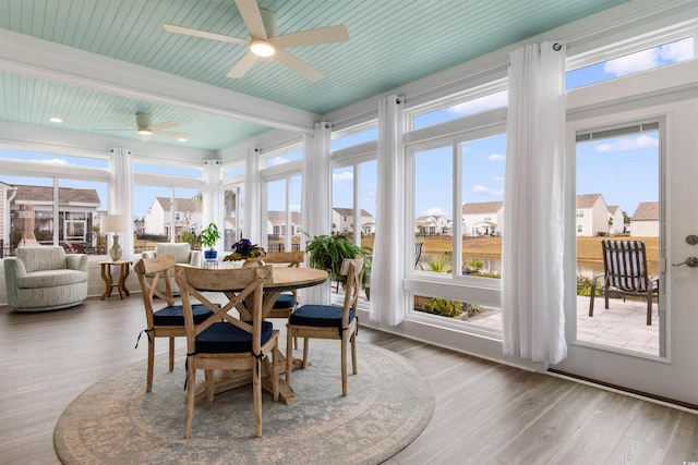 sunroom / solarium with a residential view, beam ceiling, and a wealth of natural light