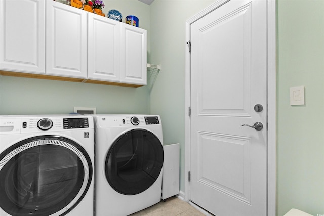 clothes washing area featuring washer and clothes dryer, cabinet space, and light tile patterned floors