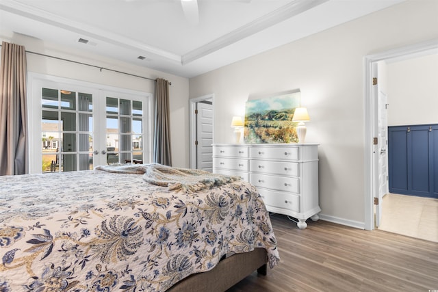 bedroom with french doors, a raised ceiling, access to exterior, visible vents, and wood finished floors