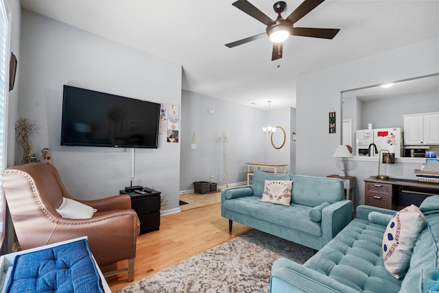 living room with light wood finished floors, a ceiling fan, and a chandelier