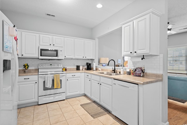 kitchen featuring white appliances, a sink, tasteful backsplash, light countertops, and white cabinets