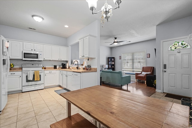 kitchen with white appliances, a sink, light tile patterned floors, tasteful backsplash, and open floor plan