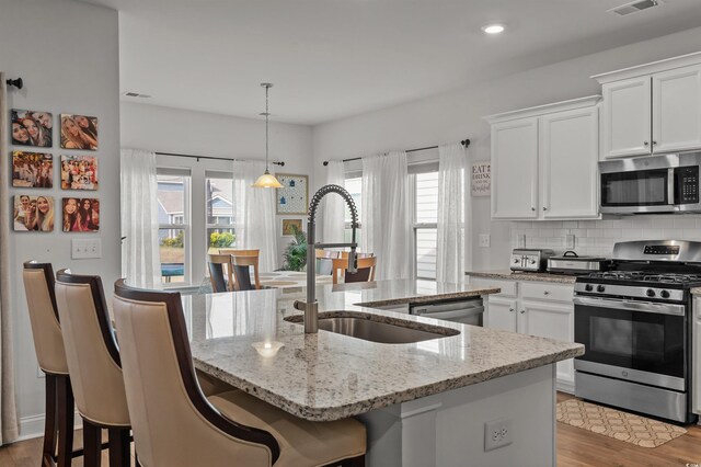 1176 Harbison Cir, Myrtle Beach, SC 29579 - kitchen featuring appliances with stainless steel finishes, a kitchen island with sink, light stone countertops, white cabinetry, and wood finished floors