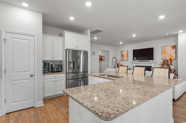 1176 Harbison Cir, Myrtle Beach, SC 29579 - kitchen with stainless steel fridge, a sink, white cabinets, a spacious island, and light wood-type flooring