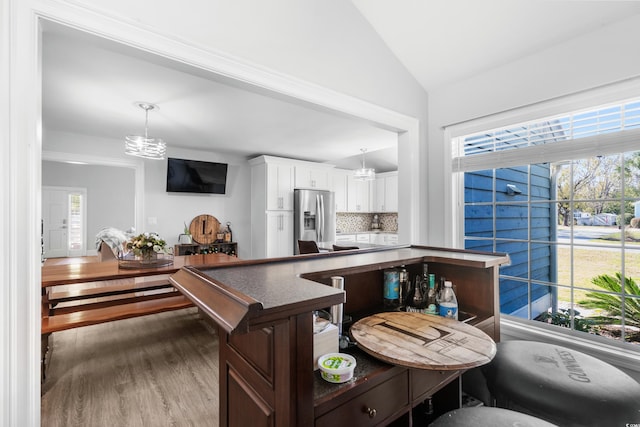 160 Shipmaster Ave, Pawleys Island, SC 29585 - kitchen featuring stainless steel refrigerator with ice dispenser, a chandelier, lofted ceiling, white cabinets, and tasteful backsplash