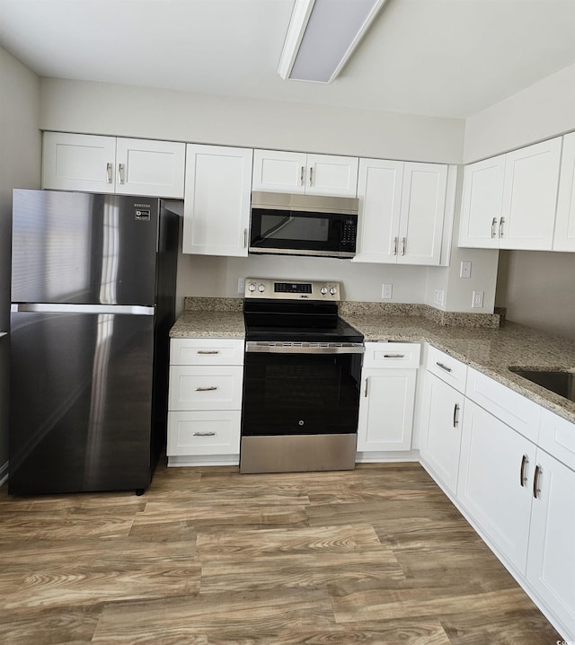 703 S 1st Ave S Unit 34D, North Myrtle Beach, SC 29582 - kitchen with stainless steel appliances, light stone countertops, white cabinetry, and light wood-style flooring