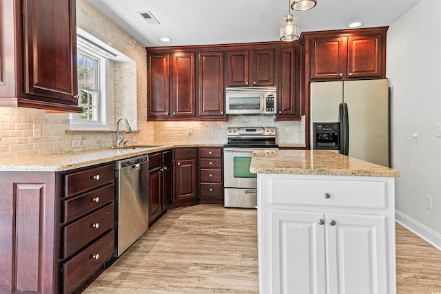 kitchen with light wood-type flooring, light stone counters, visible vents, appliances with stainless steel finishes, and a sink