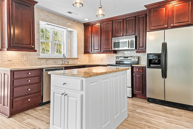kitchen with light wood-type flooring, visible vents, a sink, stainless steel appliances, and backsplash