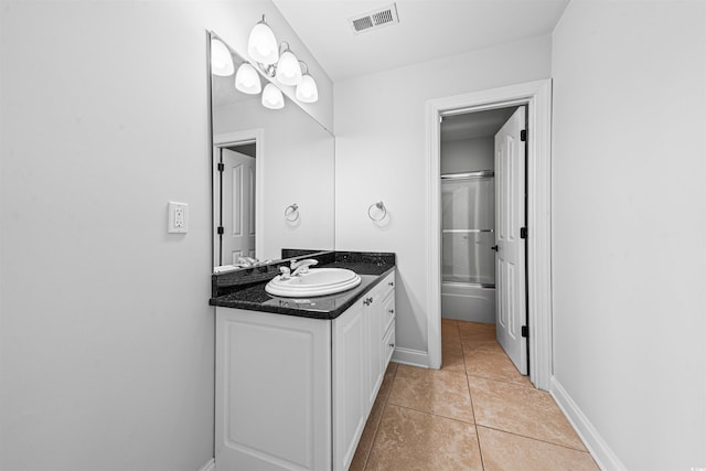 full bathroom featuring vanity, visible vents, bath / shower combo with glass door, tile patterned floors, and baseboards