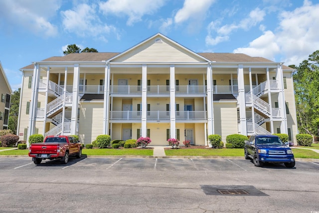 view of building exterior with uncovered parking and stairs