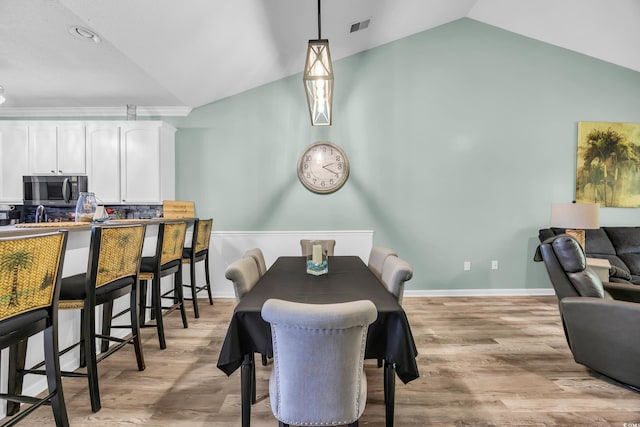 dining space featuring visible vents, light wood-type flooring, and lofted ceiling