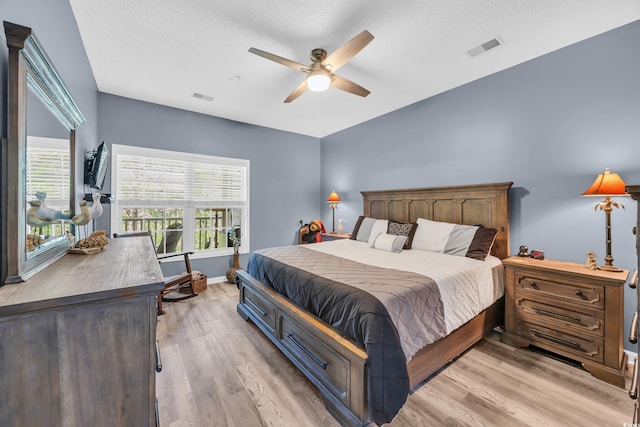 bedroom featuring light wood-style flooring, baseboards, a ceiling fan, and visible vents
