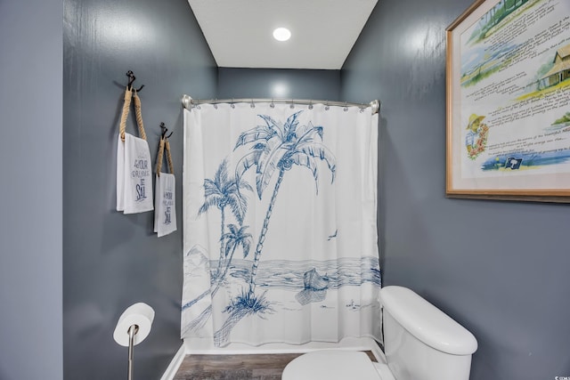 bathroom featuring a shower with shower curtain, baseboards, toilet, and wood finished floors