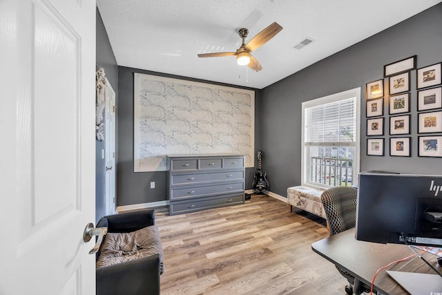 office area with light wood-style flooring, ceiling fan, baseboards, and visible vents