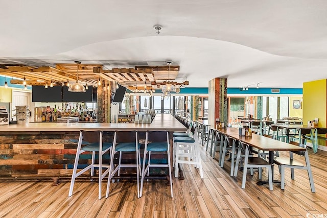 dining space featuring wood finished floors and a community bar