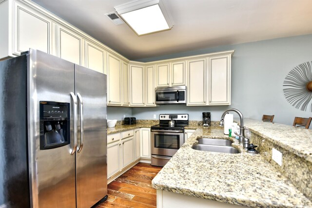 4850 Cantor Ct Unit 202, North Myrtle Beach, SC 29582 - kitchen with stainless steel appliances, a sink, a peninsula, wood finished floors, and cream cabinetry