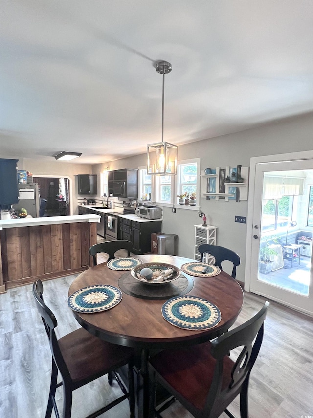 532 Medcalf Dr SW, Sunset Beach, NC 28468 - dining area with light wood-style flooring, a healthy amount of sunlight, and a chandelier