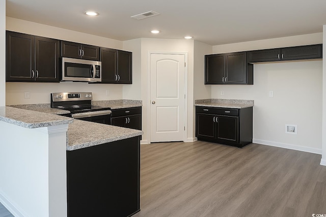 kitchen with visible vents, light countertops, appliances with stainless steel finishes, a peninsula, and light wood-style floors