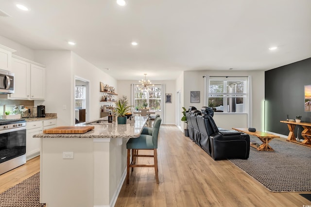 kitchen featuring stainless steel appliances, open floor plan, recessed lighting, white cabinets, and light wood-style flooring