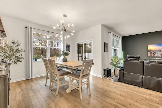 dining area with a chandelier, light wood finished floors, and baseboards
