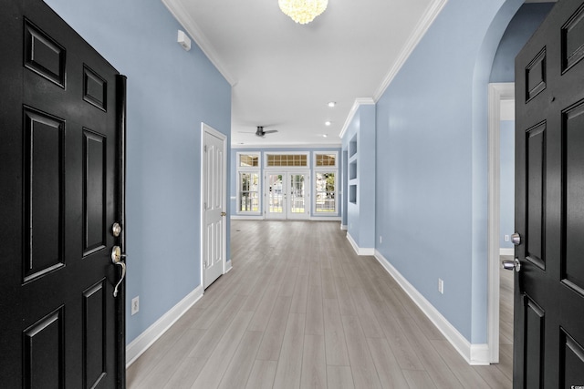 entryway with arched walkways, ornamental molding, light wood-style floors, and baseboards