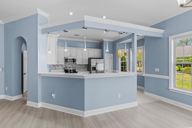 kitchen with decorative backsplash, arched walkways, stainless steel appliances, light wood finished floors, and a peninsula