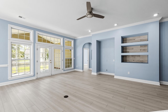 spare room with a ceiling fan, arched walkways, ornamental molding, and baseboards