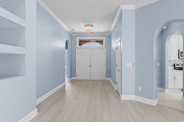 entrance foyer with arched walkways, light wood-style floors, crown molding, and baseboards