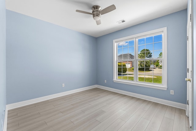 empty room with light wood-type flooring, visible vents, a ceiling fan, and baseboards