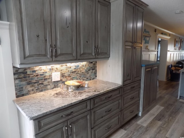 305 N Hillside Dr N Unit 103, North Myrtle Beach, SC 29582 - kitchen featuring wood finished floors, crown molding, backsplash, and light stone counters