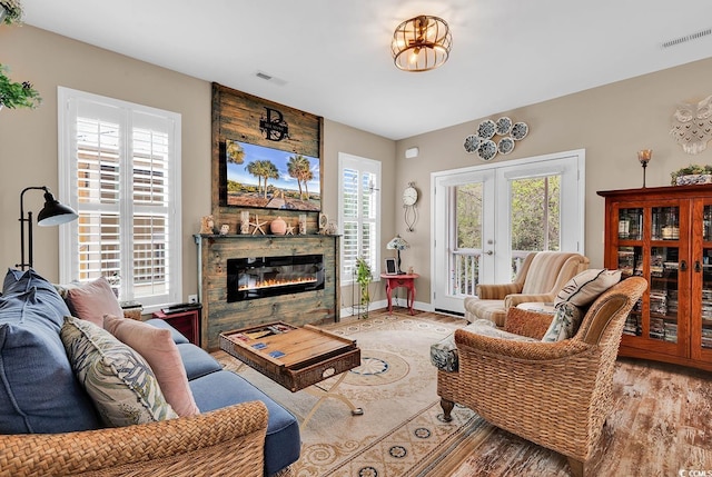 living room featuring a large fireplace, wood finished floors, visible vents, and a wealth of natural light