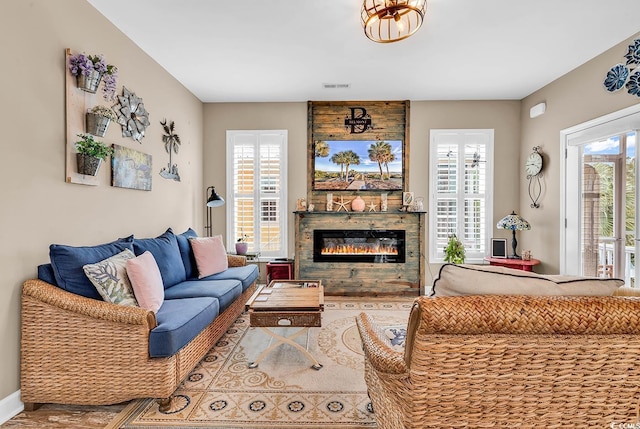 living room featuring a glass covered fireplace, wood finished floors, and visible vents