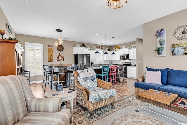 living area with recessed lighting, light wood-type flooring, and baseboards