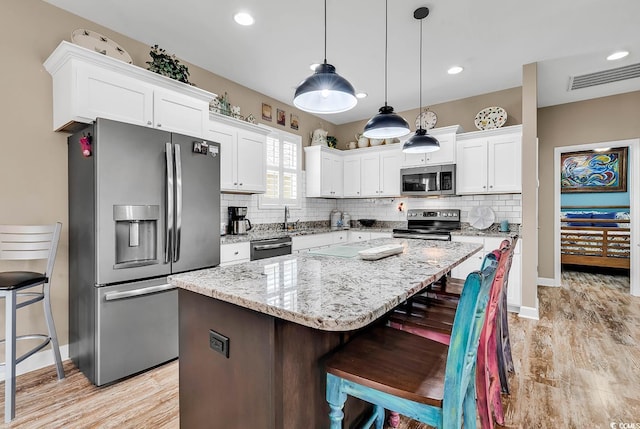 kitchen featuring white cabinets, stainless steel appliances, visible vents, and tasteful backsplash