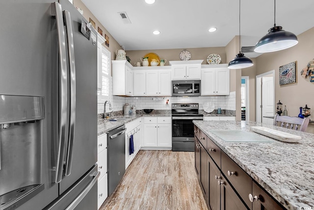 kitchen with backsplash, appliances with stainless steel finishes, hanging light fixtures, and white cabinetry