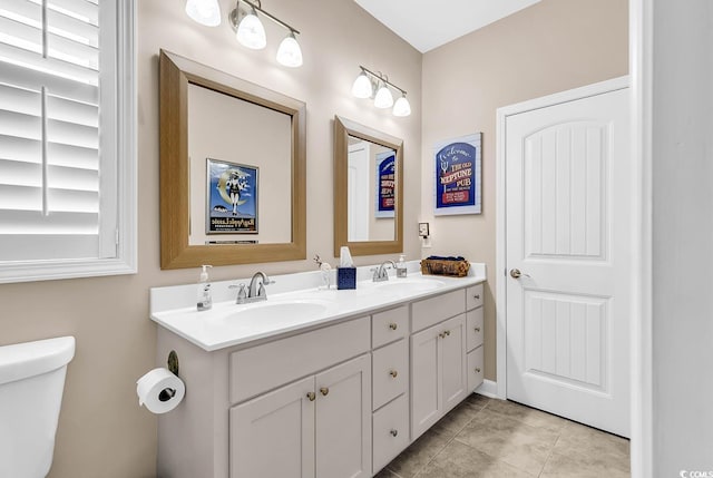bathroom with tile patterned flooring, double vanity, toilet, and a sink