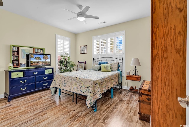 bedroom featuring baseboards, a ceiling fan, visible vents, and light wood-type flooring