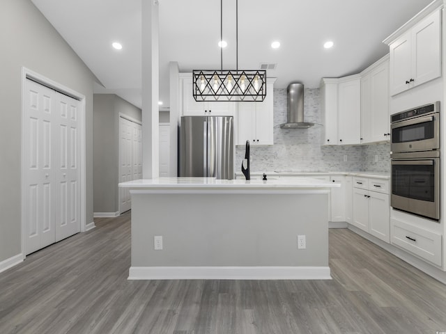 4854 Meadowsweet Dr Unit 1909, Myrtle Beach, SC 29579 - kitchen with appliances with stainless steel finishes, wall chimney range hood, decorative backsplash, a kitchen island with sink, and white cabinets