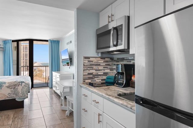 9550 Shore Dr Unit 1026, Myrtle Beach, SC 29572 - kitchen with appliances with stainless steel finishes, tasteful backsplash, white cabinets, crown molding, and light tile patterned flooring