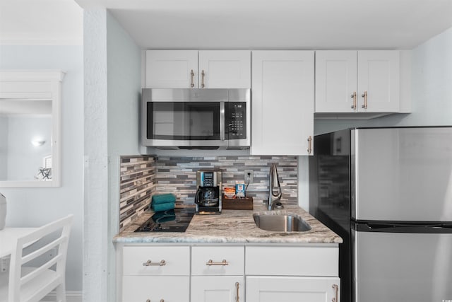 9550 Shore Dr Unit 1026, Myrtle Beach, SC 29572 - kitchen featuring appliances with stainless steel finishes, a sink, backsplash, white cabinetry, and light stone countertops