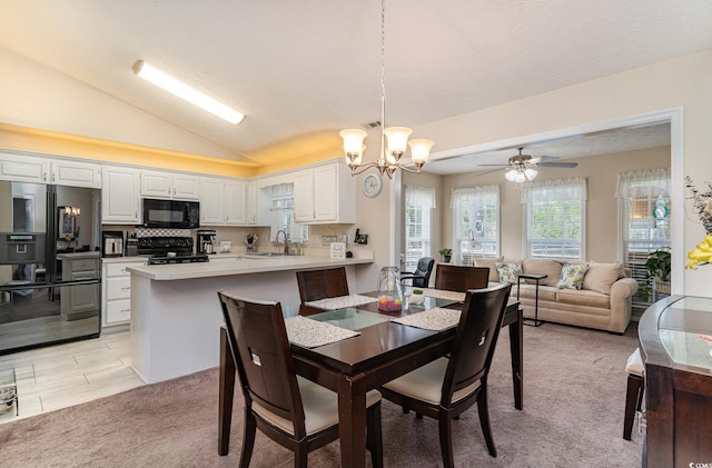 dining space with a textured ceiling, light carpet, lofted ceiling, and ceiling fan with notable chandelier