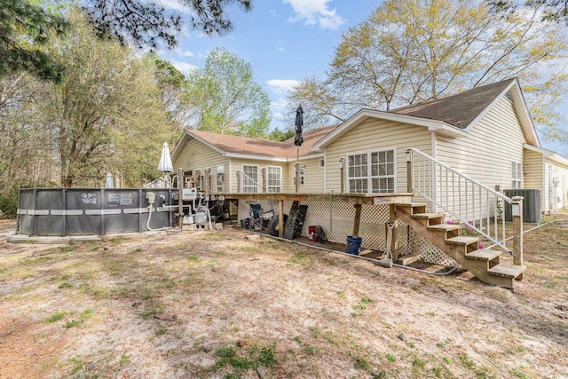 rear view of house featuring a shingled roof, central air condition unit, stairway, and a deck